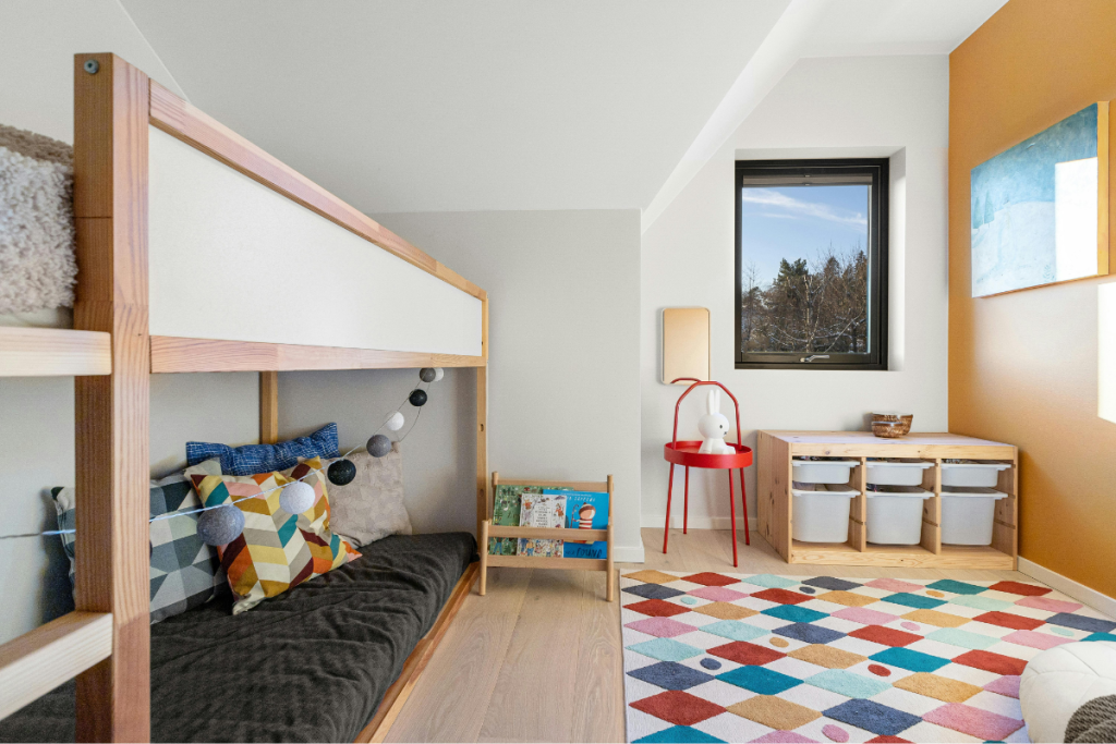 Bright, organized kids’ bedroom with cozy reading nook, colorful rug, and toy storage, offering sensory-friendly home ideas for creating a nurturing space for neurodivergent children.