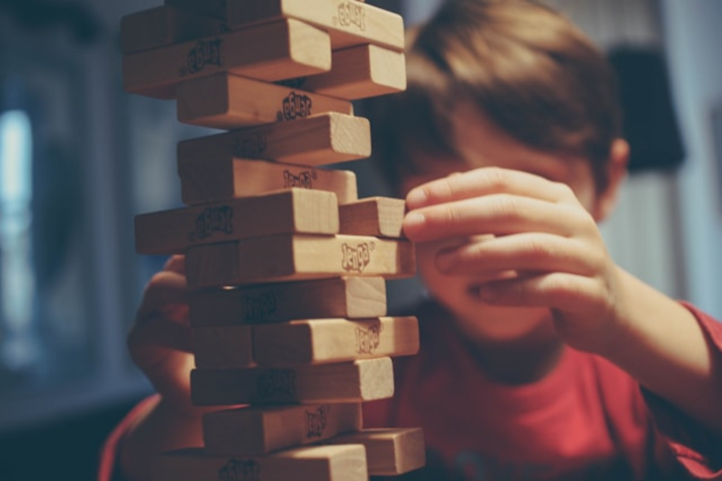 Child carefully playing Jenga, focusing on balance and strategy, symbolizing how neurodivergent kids build problem-solving skills through play.