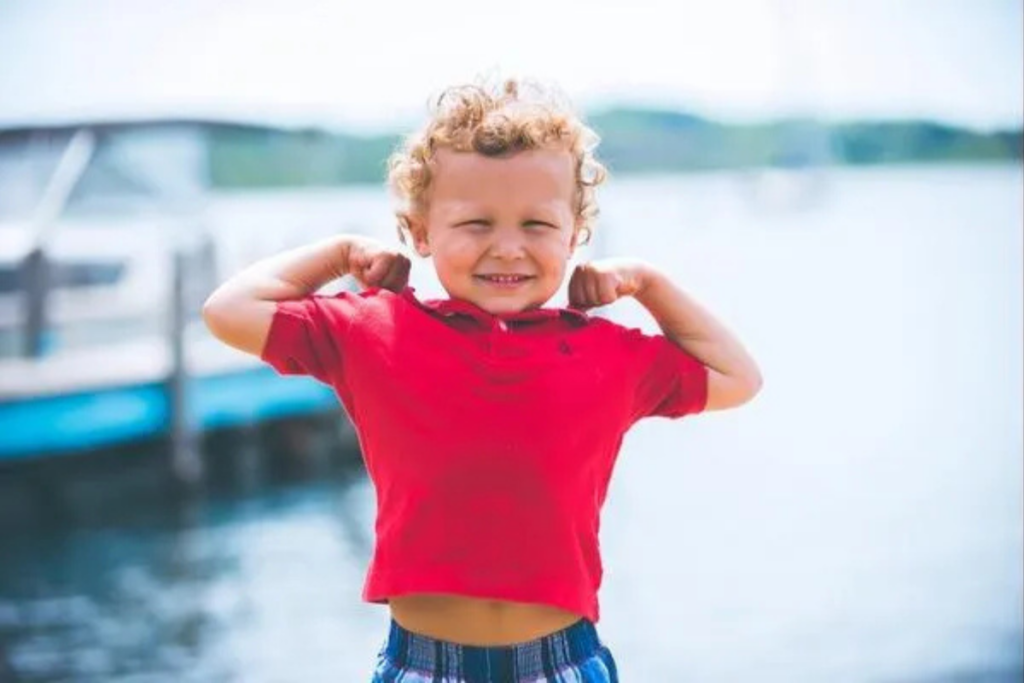 Smiling child flexing muscles at the waterfront, symbolizing confidence and parent rights in special education.