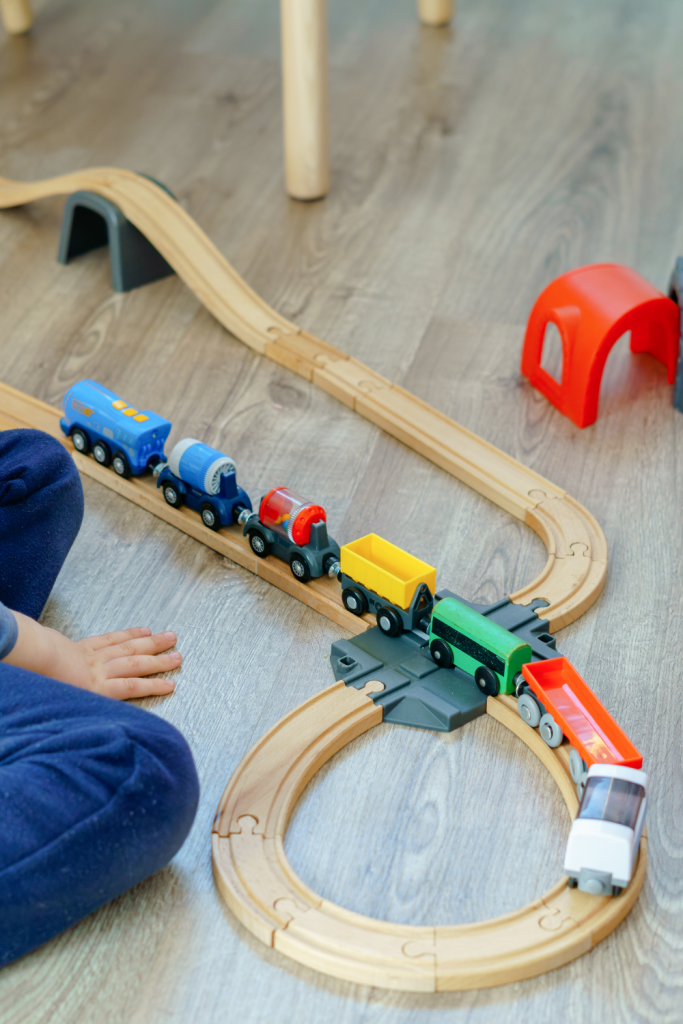 ND child playing with a colorful wooden train set, showing how nurturing special interests in children builds focus and joy.