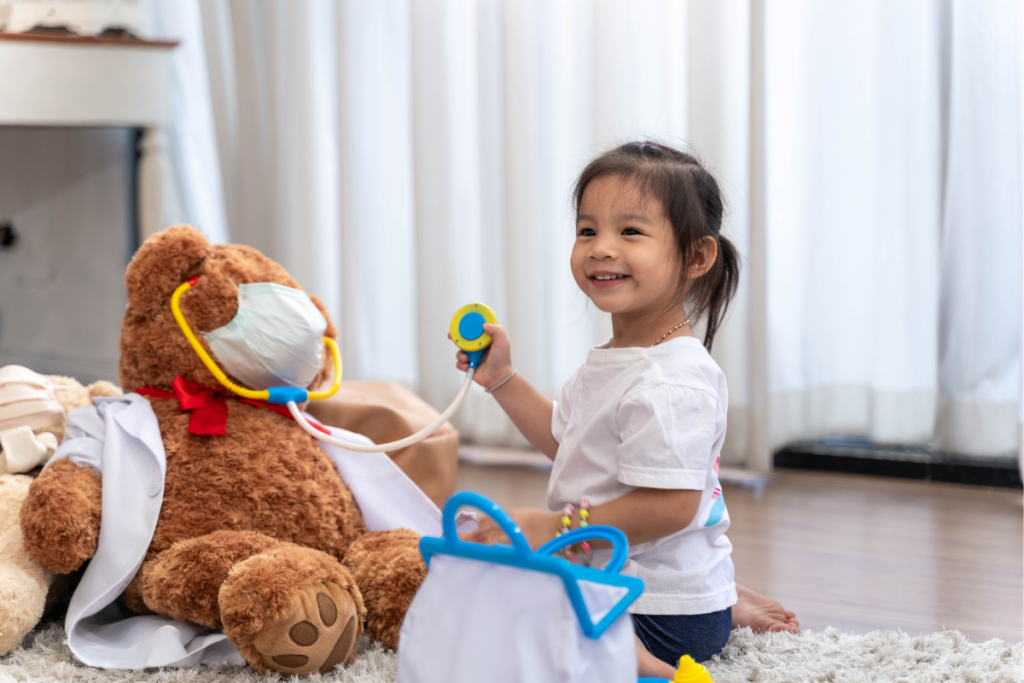 Smiling ND child roleplaying as a doctor with a teddy bear patient, showing the power of supporting special interests in children.