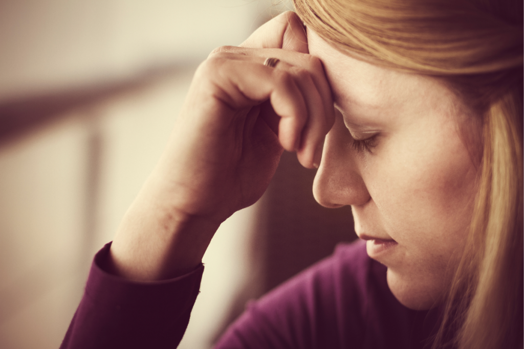 A mother resting her head in her hand, reflecting maternal guilt and emotional exhaustion after a late or missed diagnosis.