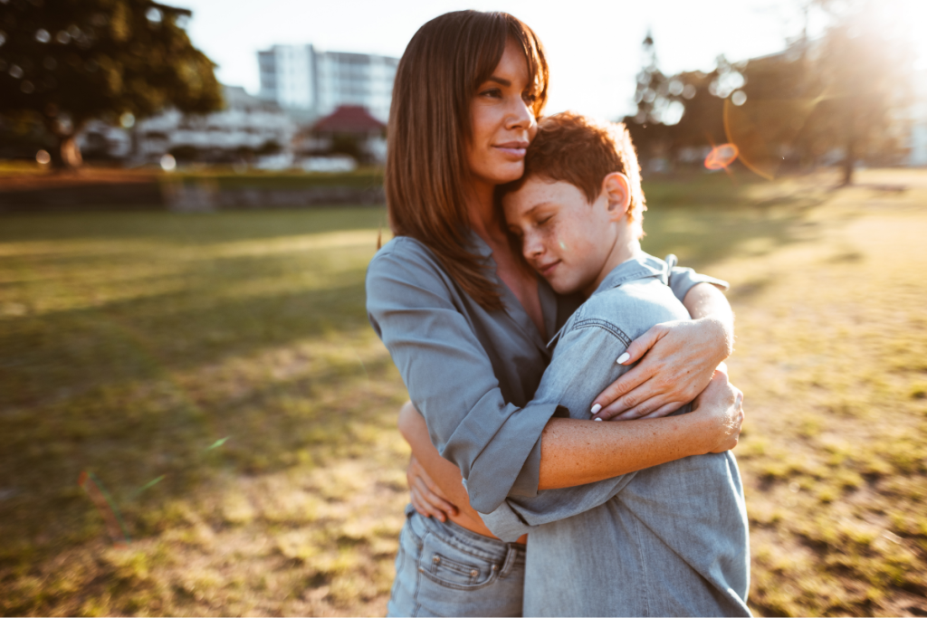 A mother holding her child close outdoors, reflecting maternal guilt, protection, and reassurance after a late or missed diagnosis.