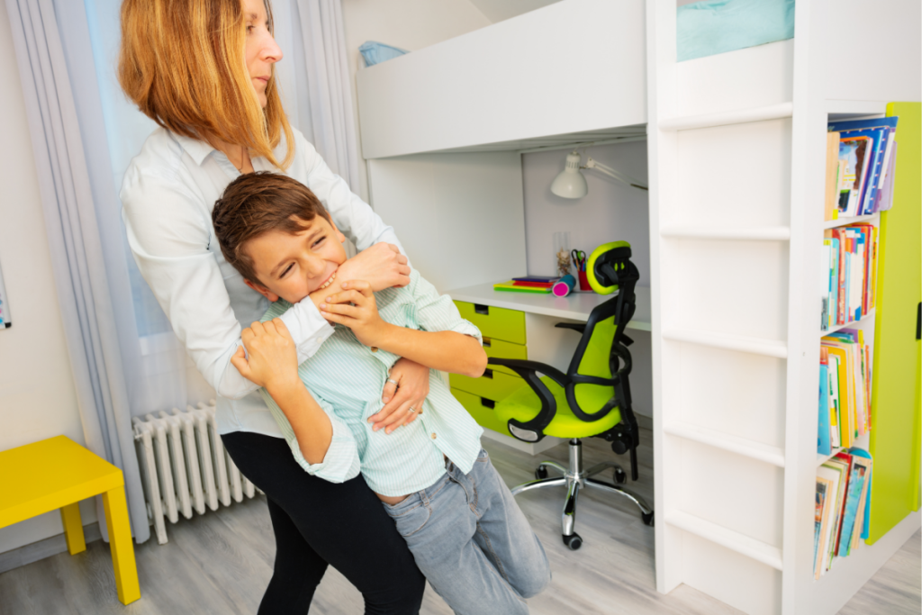 A mother holding her child in a home study space, showing the support families provide when schools don’t see the problem and a child needs help regulating.