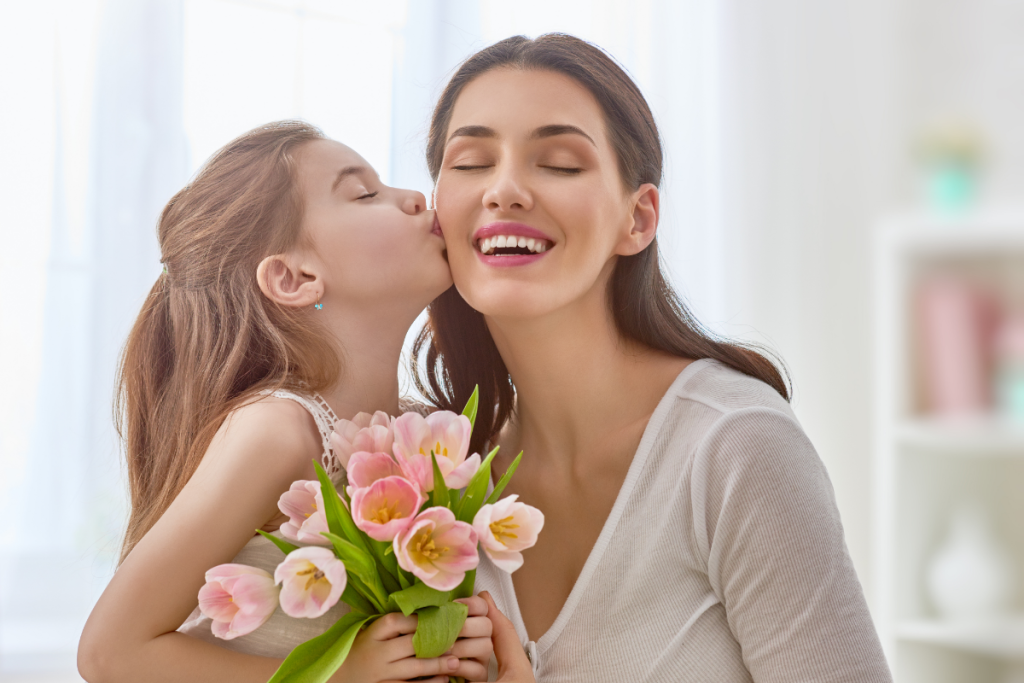 A child kissing their mother on the cheek while holding flowers, representing the bond families protect even when schools don’t see the problem.